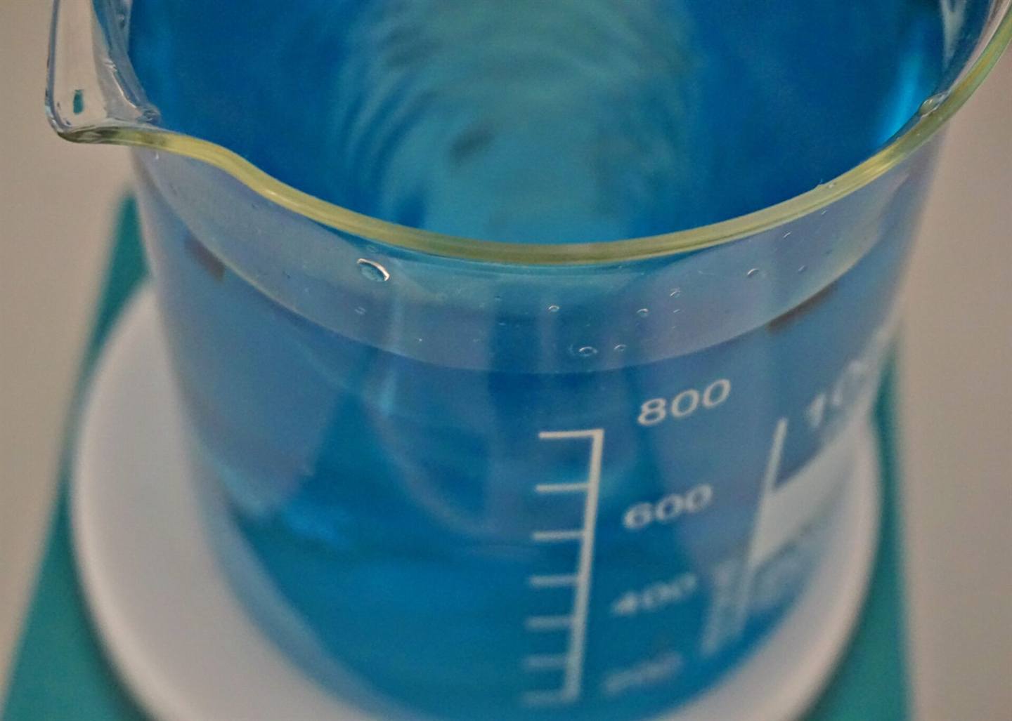 A laboratory beaker holding a blue formulation, on a stir plate at The NuCLab